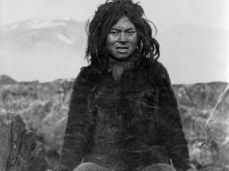 A historic photograph of an Inuit guide, who wears traditional skin and hide clothing. 